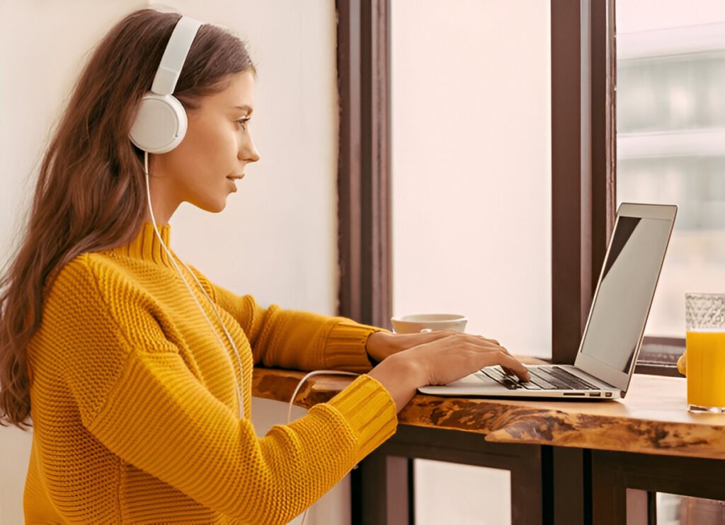 Young woman with headphones on laptop – 7 student side hustles.